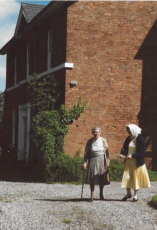 A couple of people walking in front of a brick building

Description automatically generated