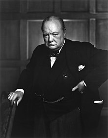 Churchill wearing a suit, standing and holding a chair