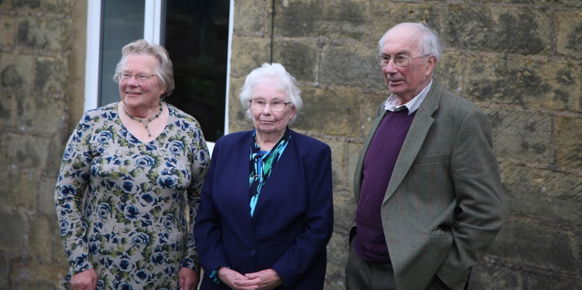 A group of old people standing outside a building

Description automatically generated