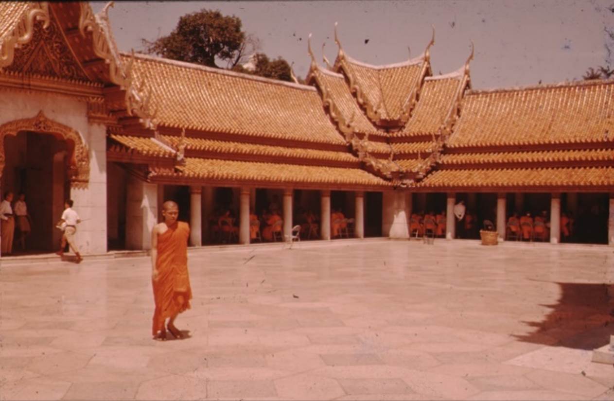 A person in an orange robe standing in front of a building

Description automatically generated with medium confidence