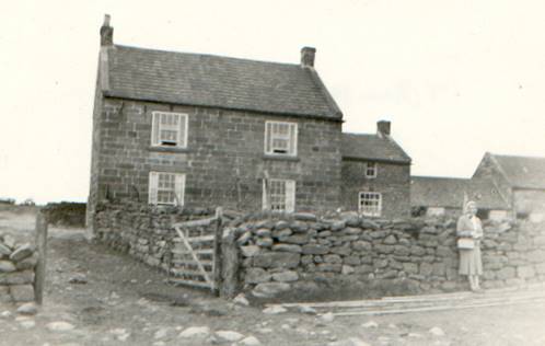 A couple of people standing in front of a stone house

Description automatically generated