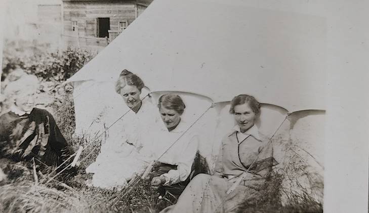 A group of women sitting in a field

Description automatically generated