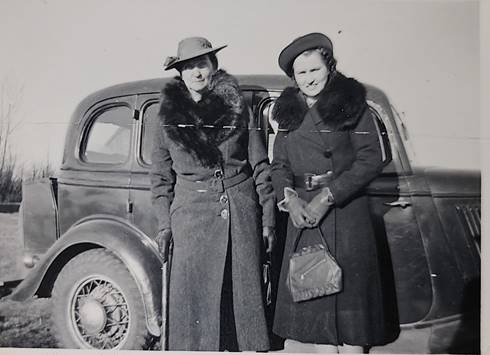 A couple of women standing next to a car

Description automatically generated