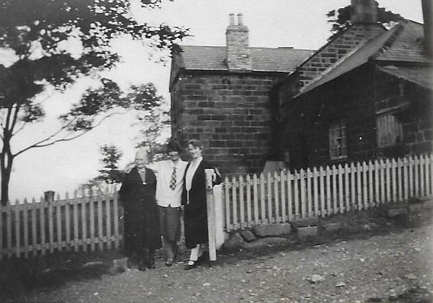 A black and white photo of a person walking by a fence

Description automatically generated