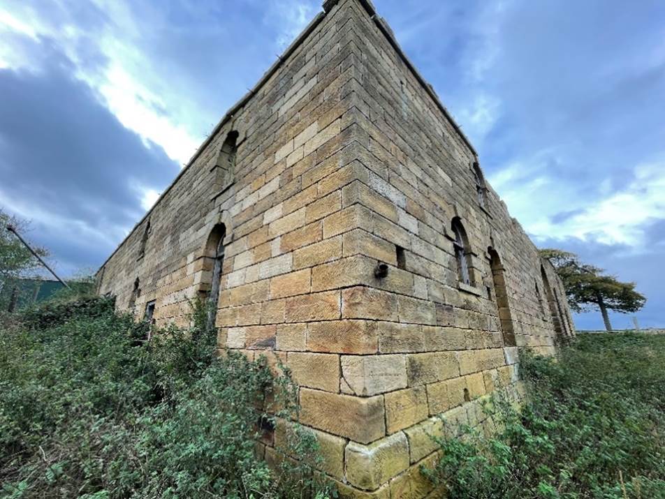 A stone building with plants growing on it

Description automatically generated