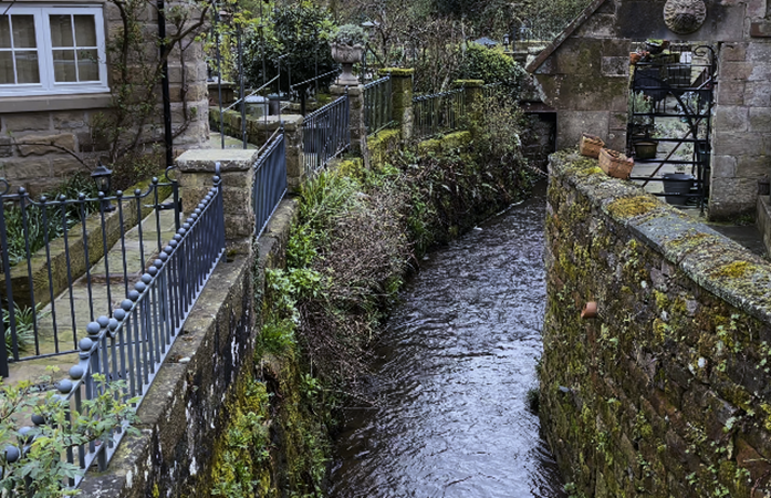 A river running through a stone wall

Description automatically generated