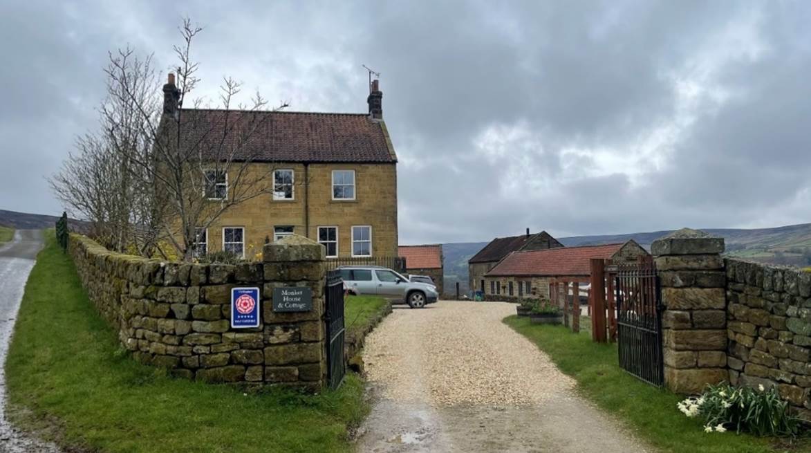 A dirt road leading to a stone wall

Description automatically generated