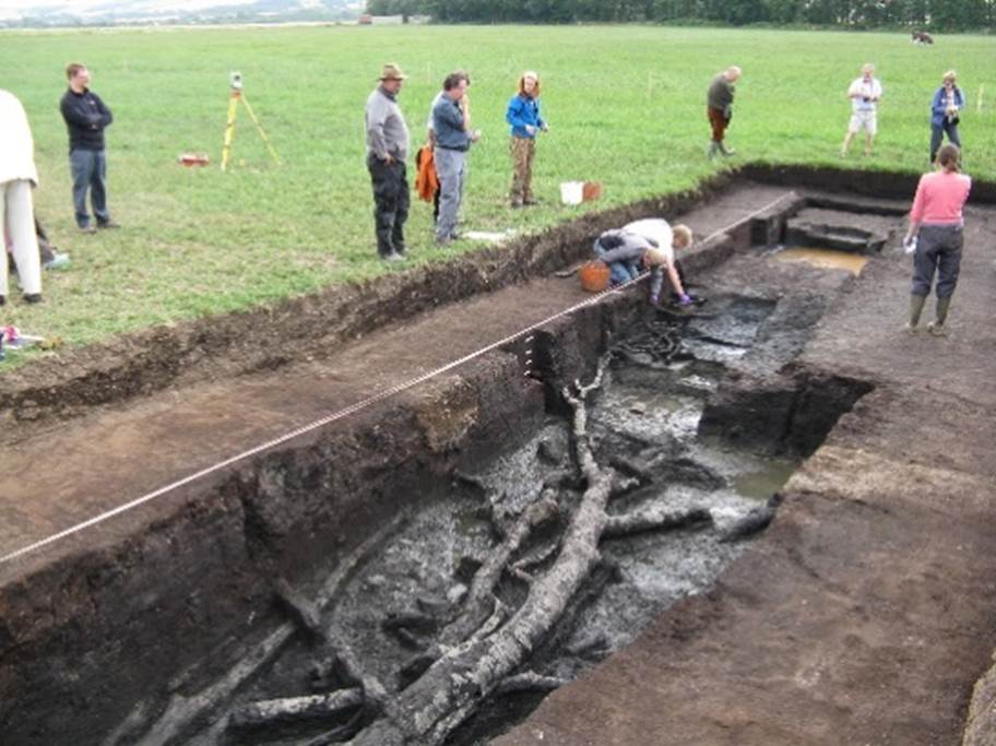 A group of people standing around a trench

Description automatically generated