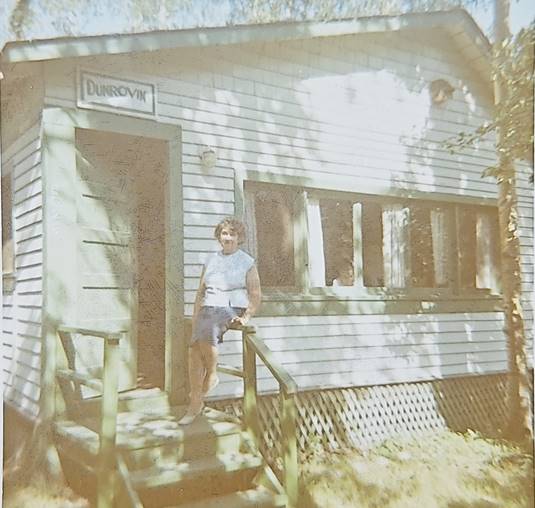 A person standing on a porch of a house

Description automatically generated