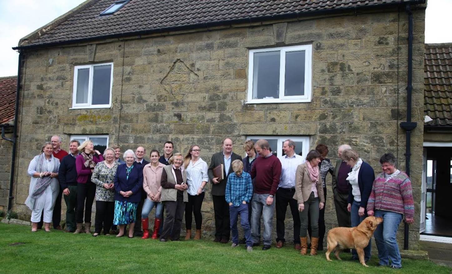 A group of people standing in front of a stone building

Description automatically generated