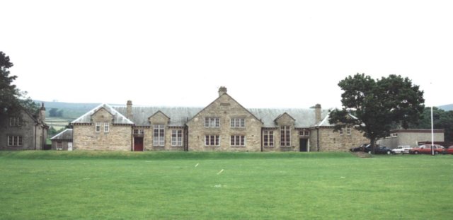 A large stone building with a lawn

Description automatically generated