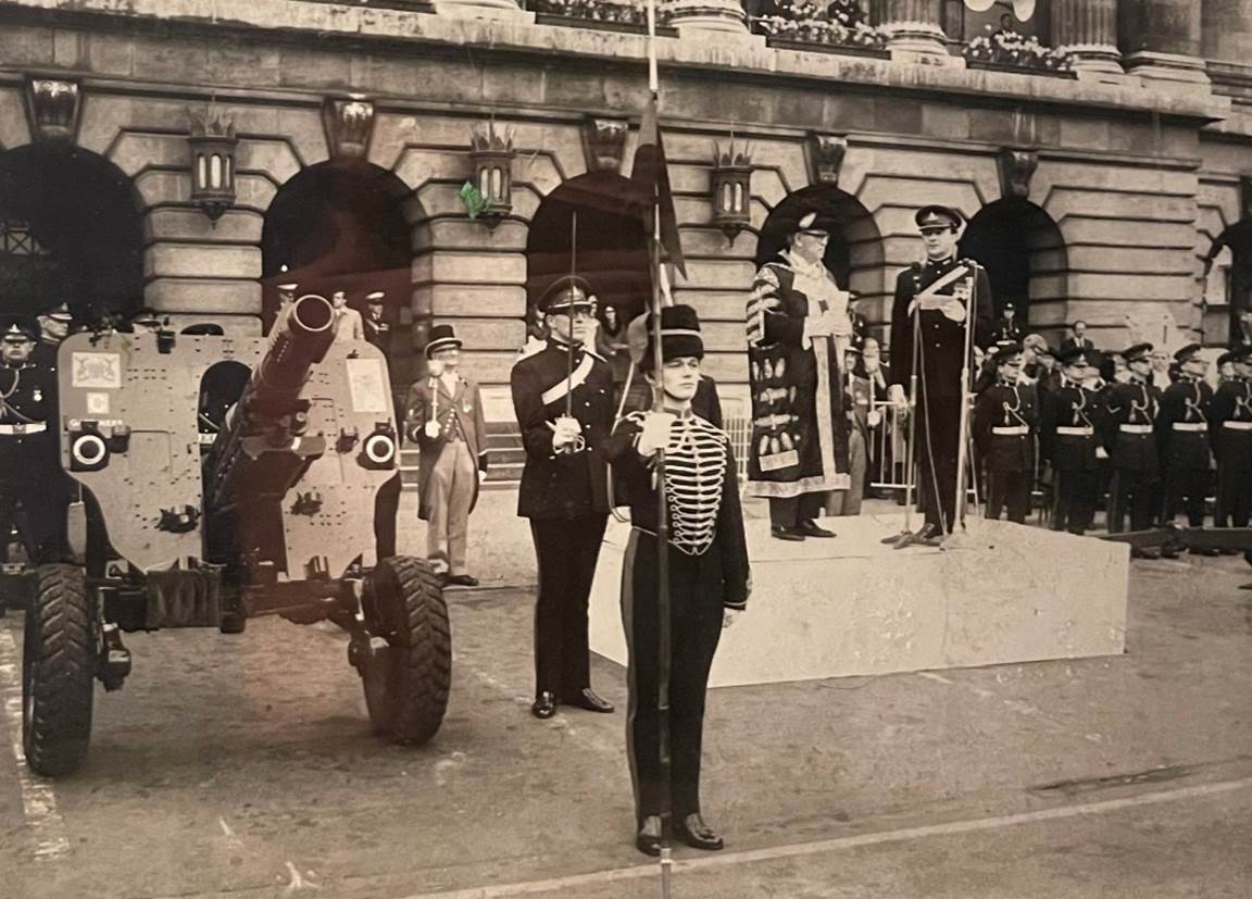 A group of men in uniform standing in front of a cannon

Description automatically generated