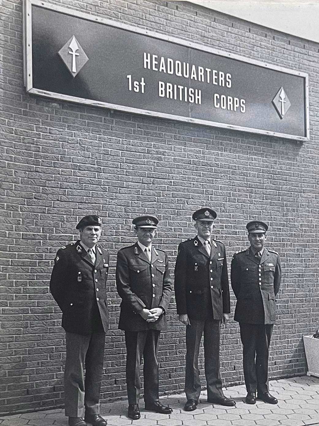 A group of men standing in front of a brick building

Description automatically generated with medium confidence