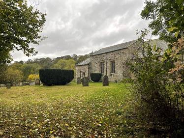 A stone building with a cemetery and trees

Description automatically generated