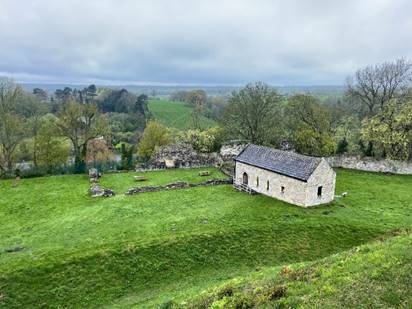 A stone building in a grassy field

Description automatically generated