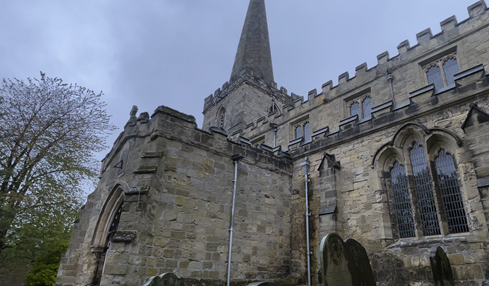 A stone building with a pointed tower

Description automatically generated