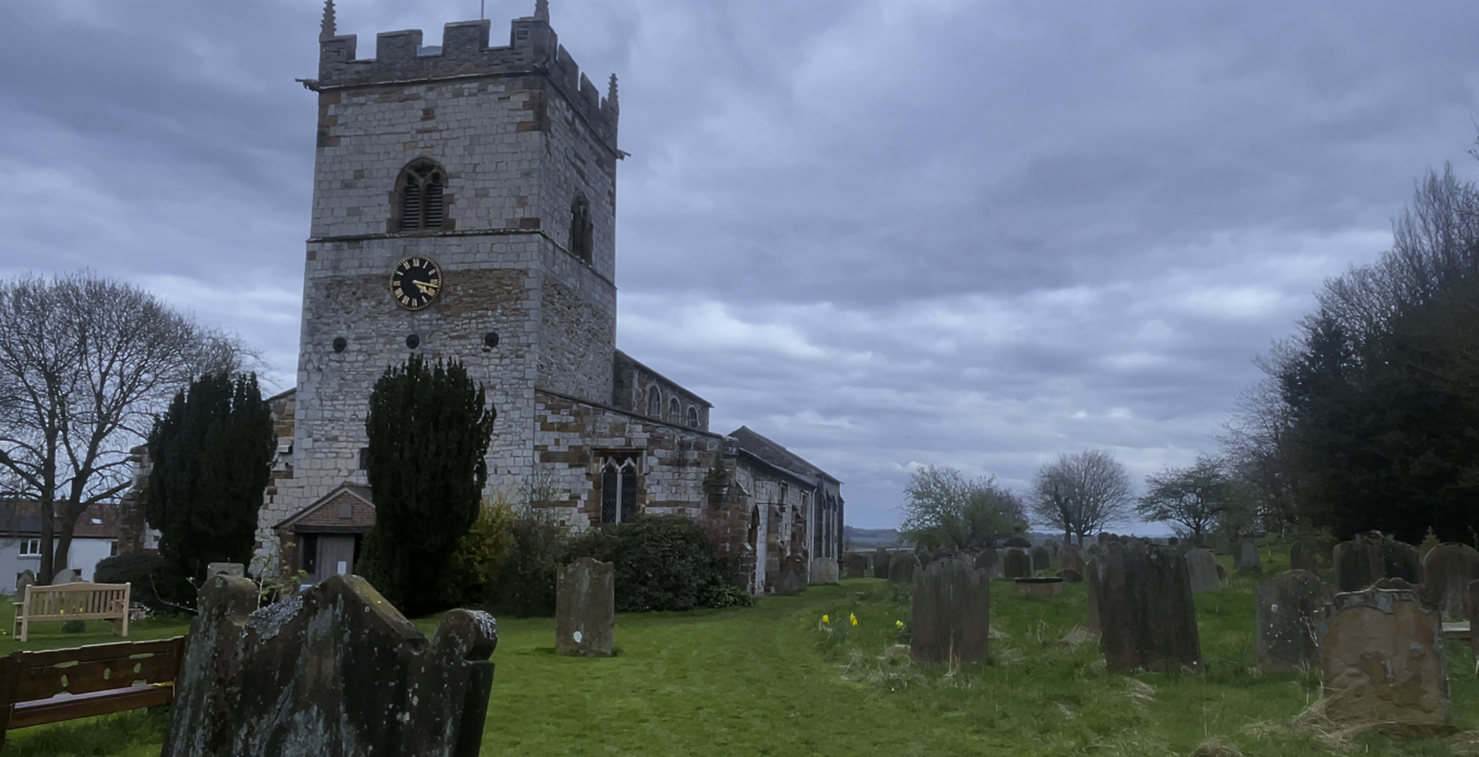 A stone building with a clock tower and a cemetery

Description automatically generated