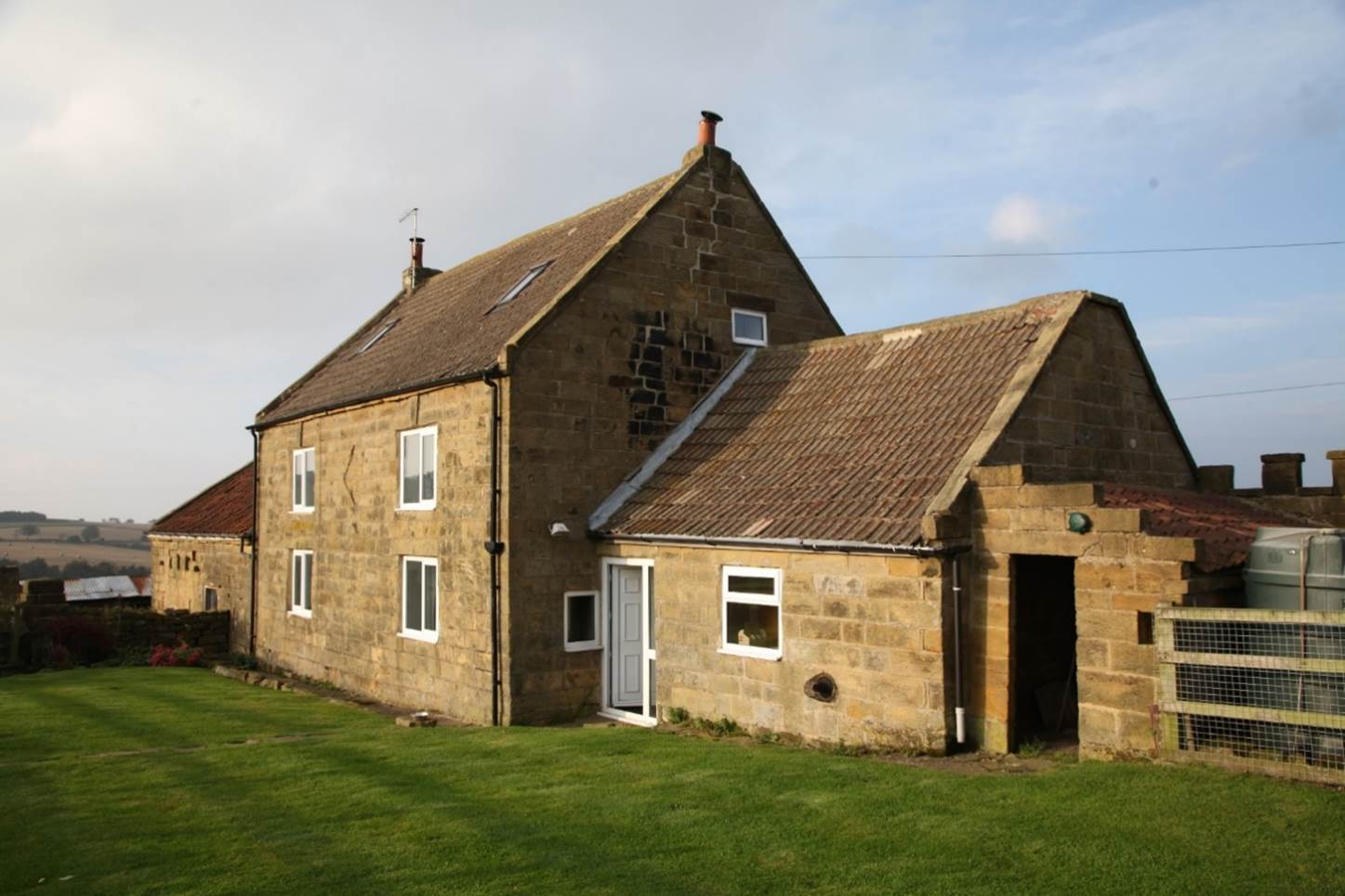 A stone house with grass in front

Description automatically generated