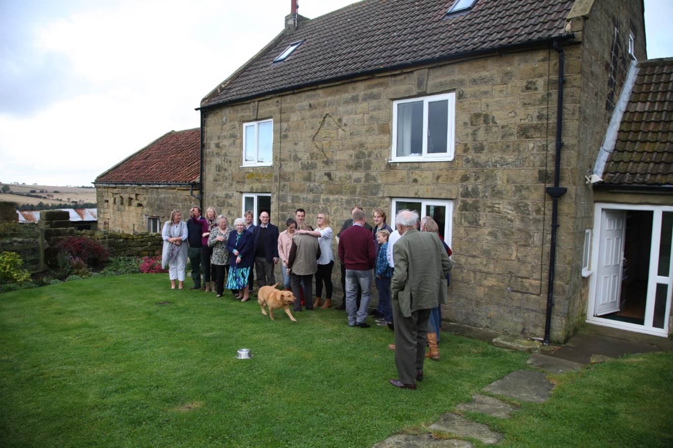 A group of people standing in a line outside a house

Description automatically generated