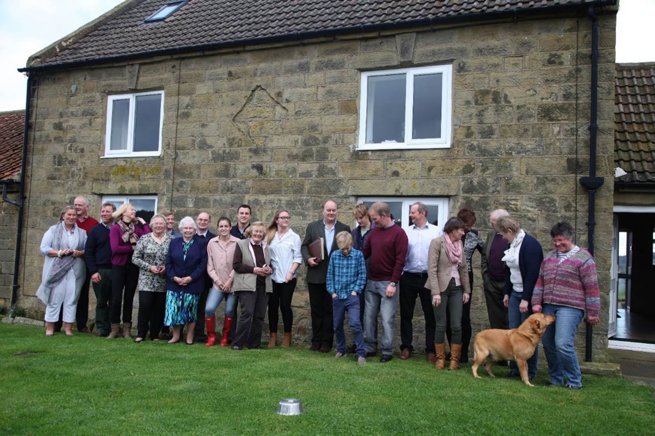 A group of people standing in front of a stone building

Description automatically generated