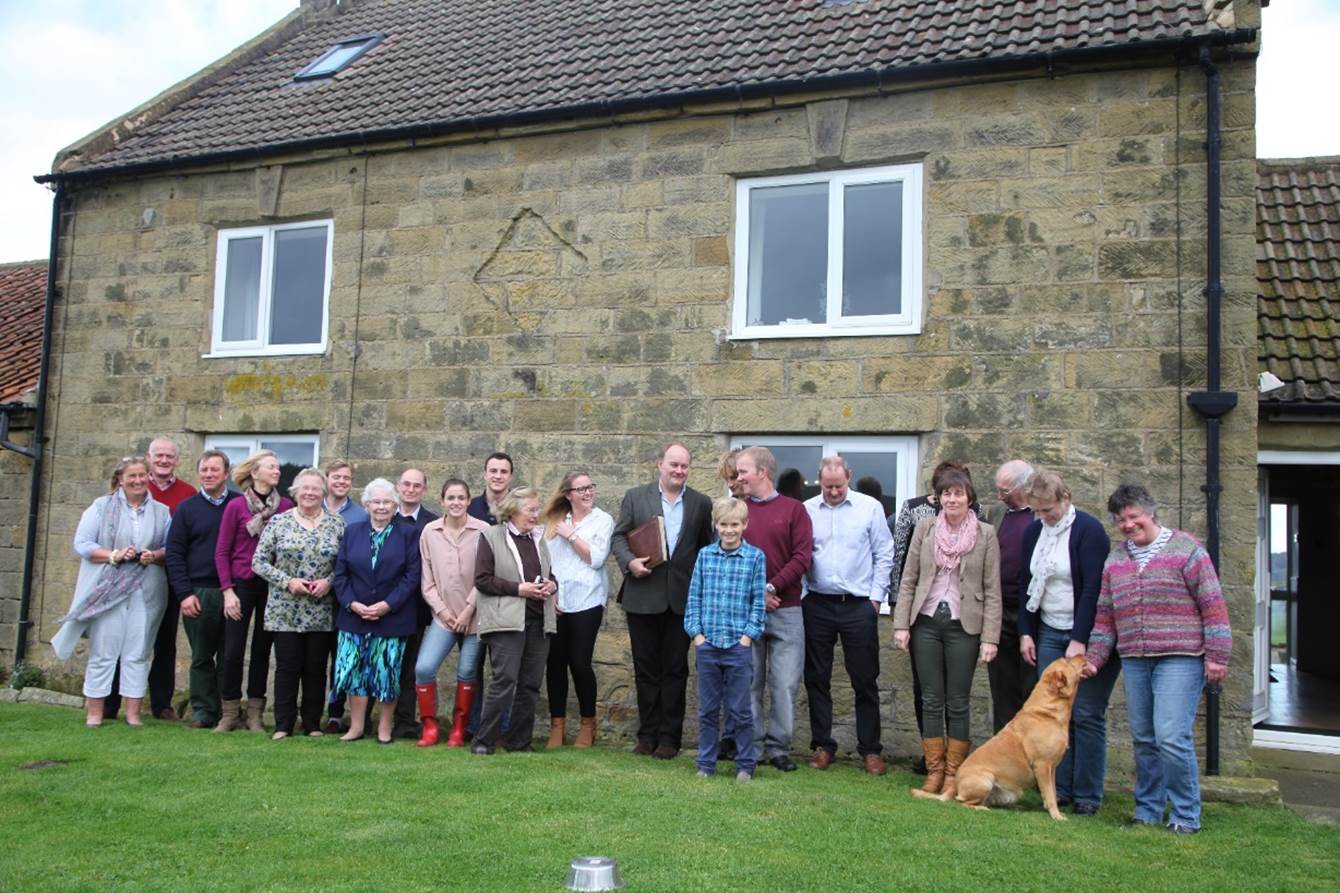 A group of people standing in front of a stone building

Description automatically generated