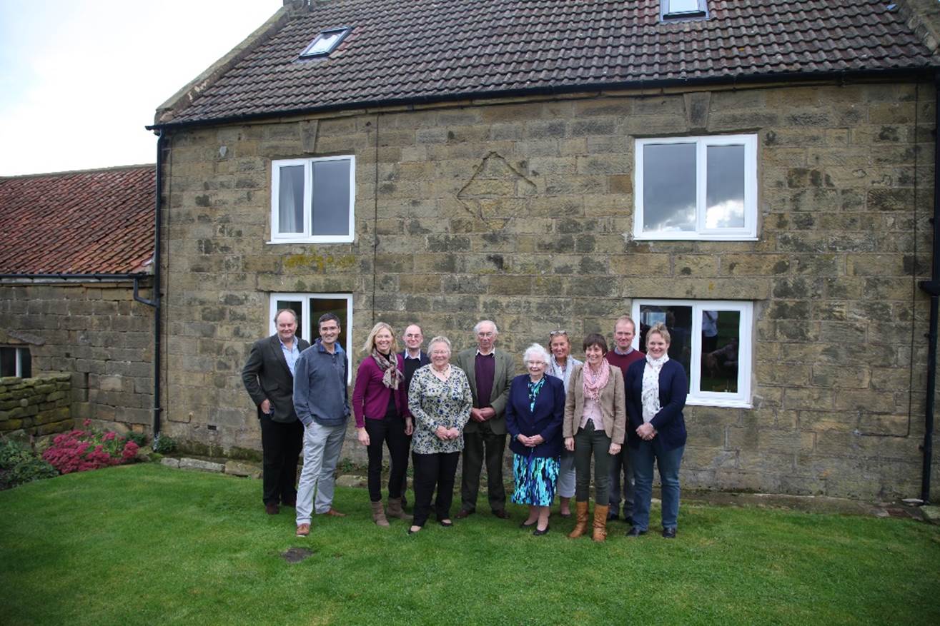 A group of people standing in front of a house

Description automatically generated