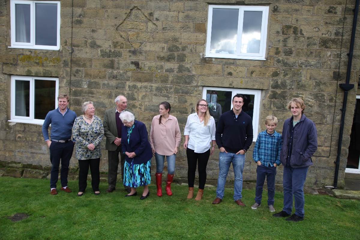 A group of people standing in front of a stone building

Description automatically generated