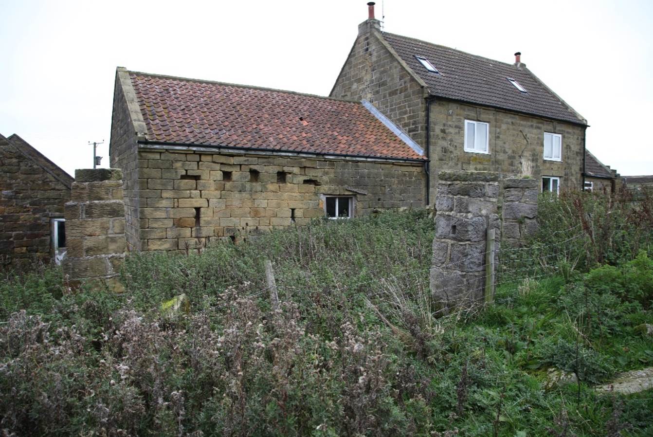 A stone house with a stone wall

Description automatically generated