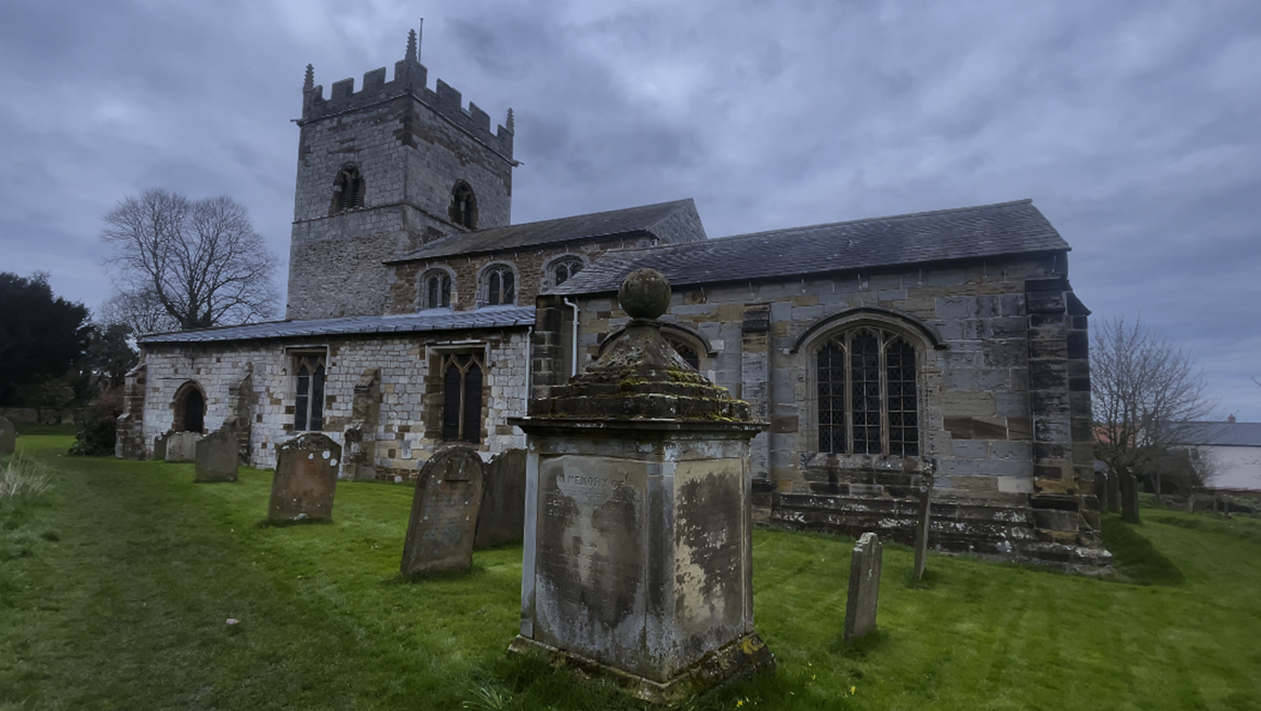 A stone building with a stone tower and a cemetery

Description automatically generated