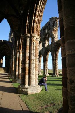 A person standing under a stone arch

Description automatically generated