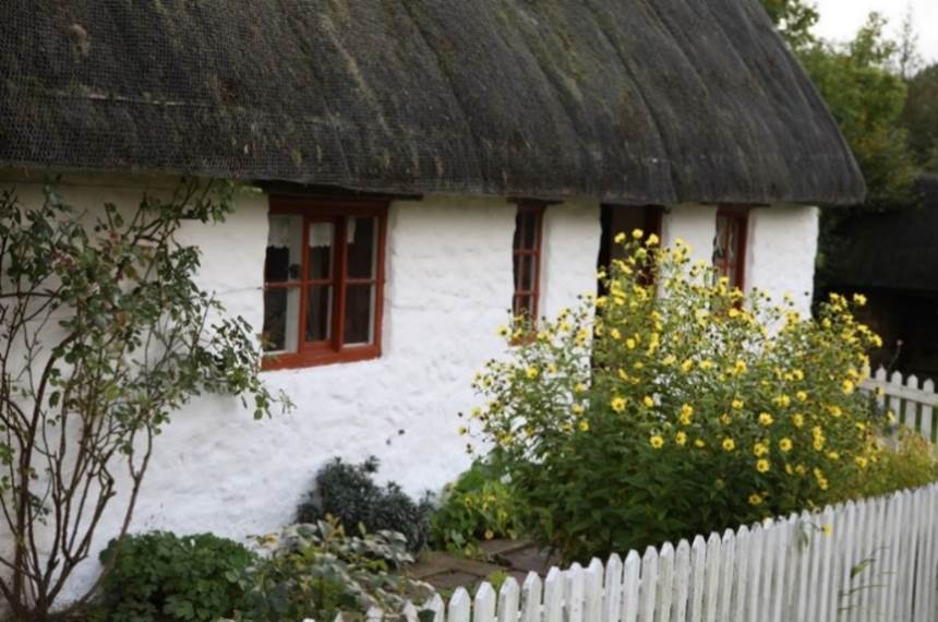 A white house with a thatched roof

Description automatically generated