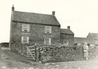 A couple of people standing in front of a stone house

Description automatically generated