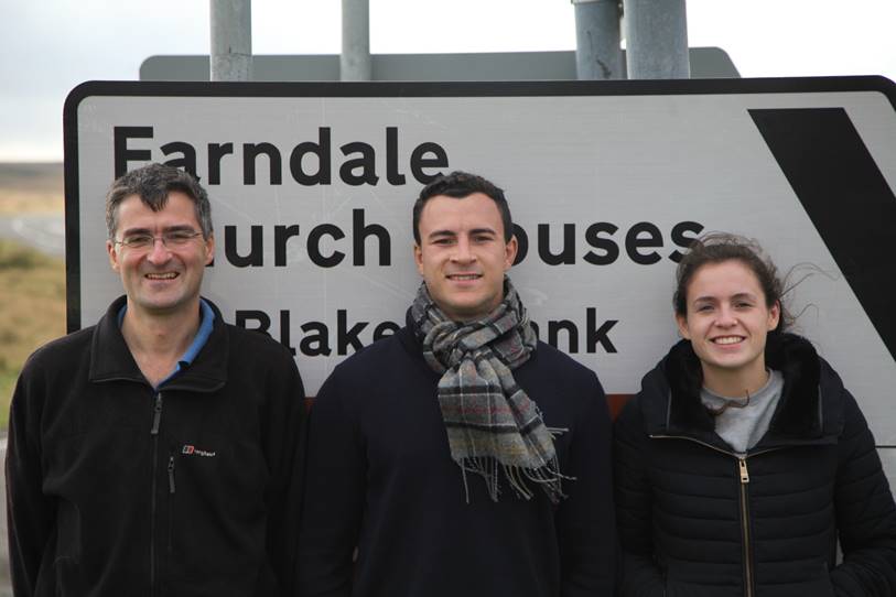 A group of people standing in front of a sign

Description automatically generated