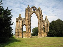 A stone arch with trees in the background

Description automatically generated