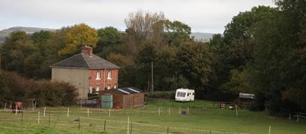 A house and camper in a field

Description automatically generated