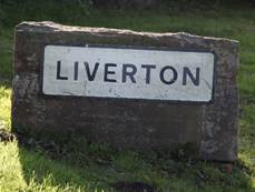 A sign on a stone in the grass

Description automatically generated