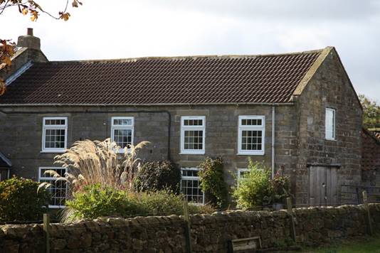 A stone house with a stone wall

Description automatically generated