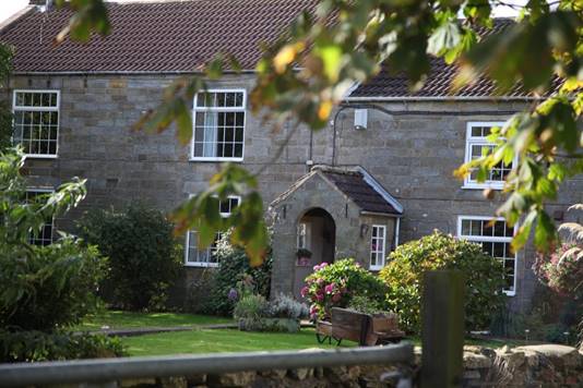 A stone building with a garden

Description automatically generated