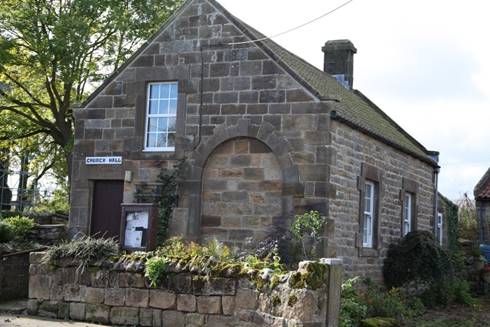 A stone house with a stone wall

Description automatically generated