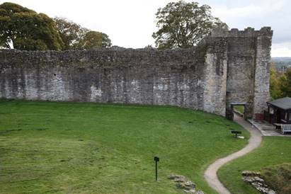 A stone wall with a green lawn

Description automatically generated