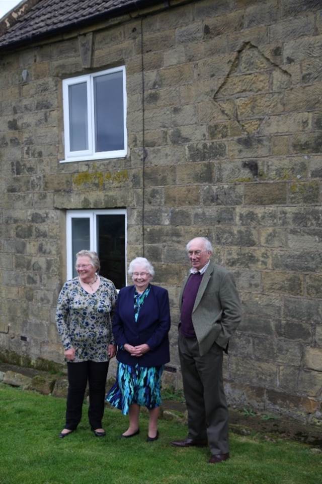 A group of people standing outside a brick building

Description automatically generated