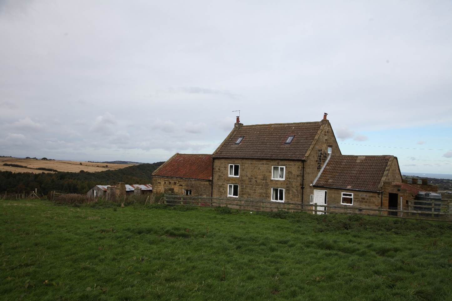 A stone house with a grassy field

Description automatically generated