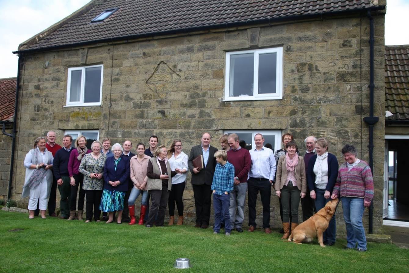 A group of people standing in front of a house

Description automatically generated