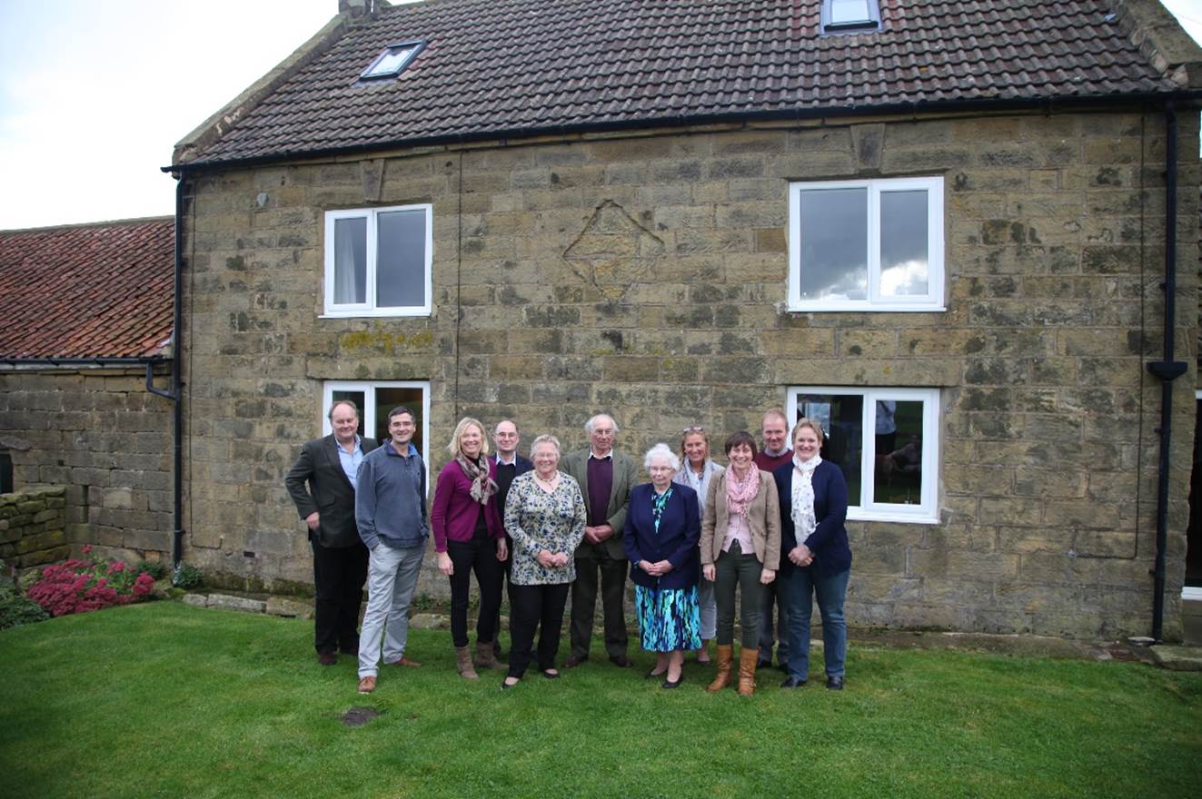 A group of people standing in front of a stone building

Description automatically generated