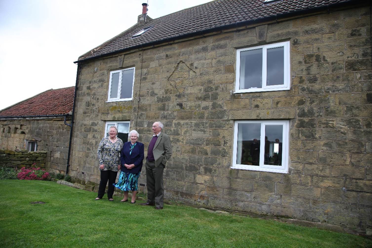 A group of people standing in front of a house

Description automatically generated