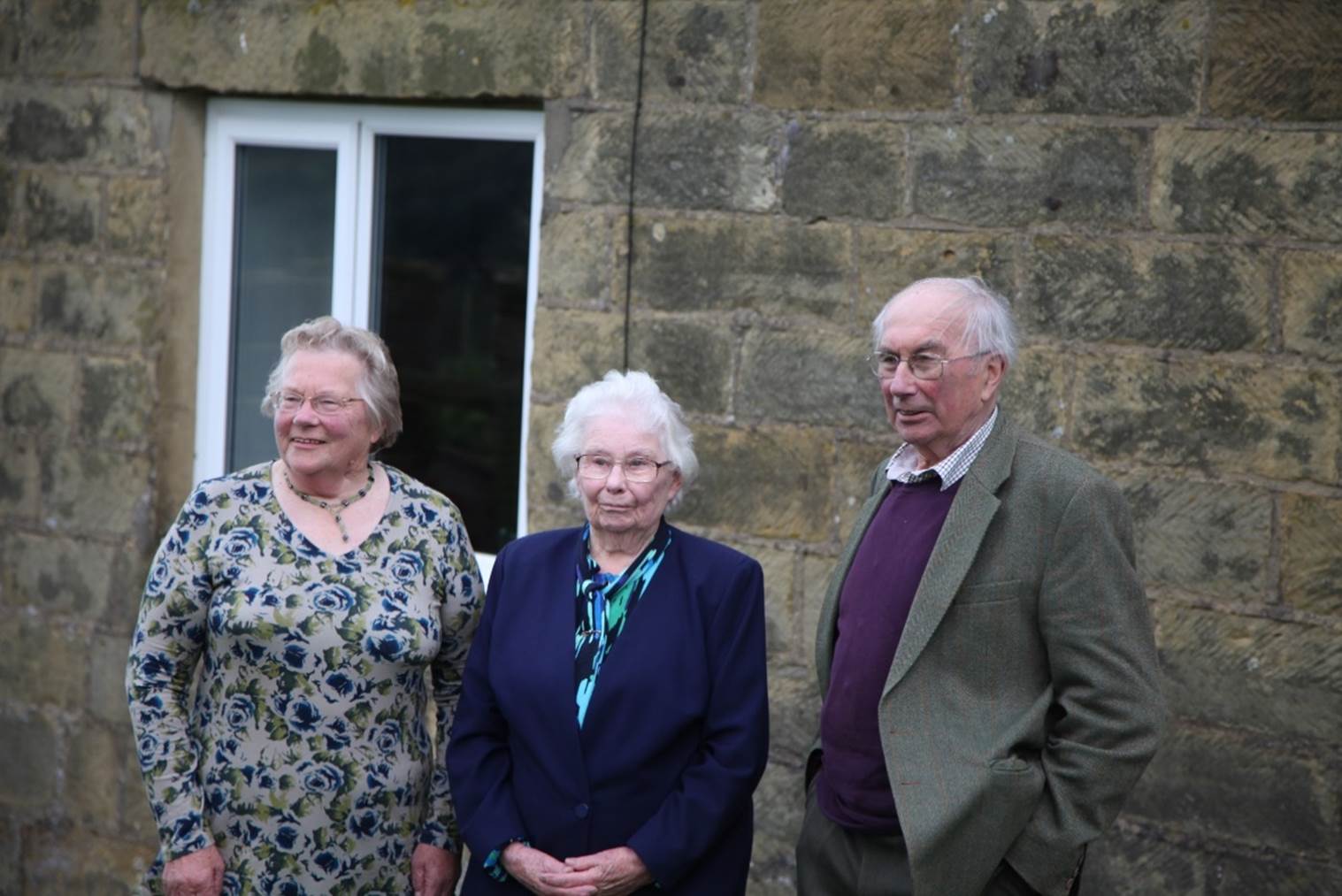 A group of old people standing outside a building

Description automatically generated