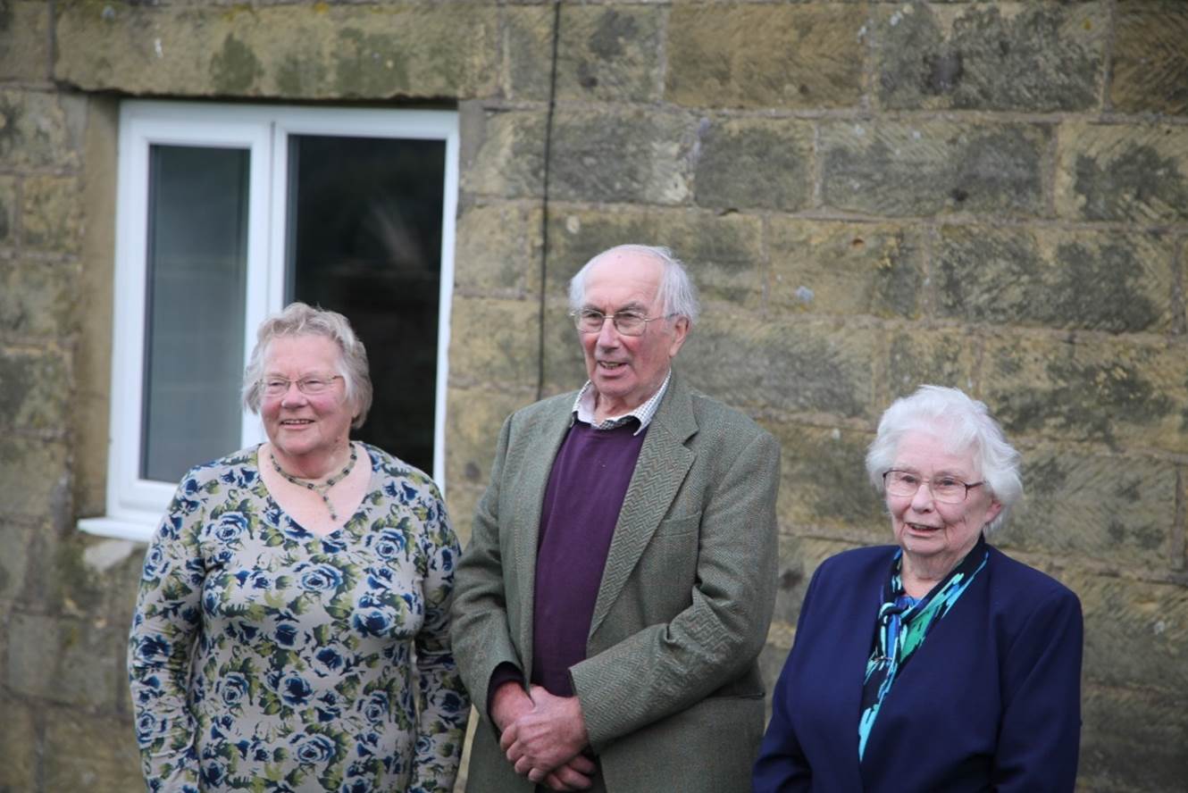 A group of old people standing outside a building

Description automatically generated