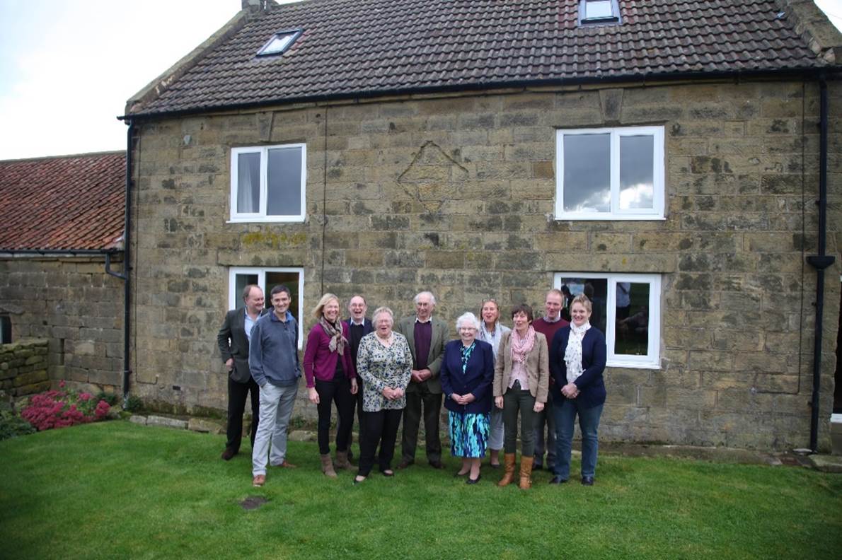 A group of people standing in front of a house

Description automatically generated