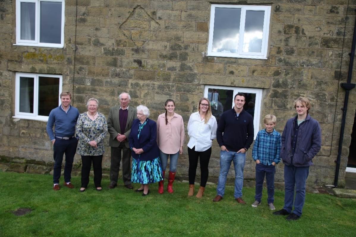 A group of people standing in front of a stone building

Description automatically generated