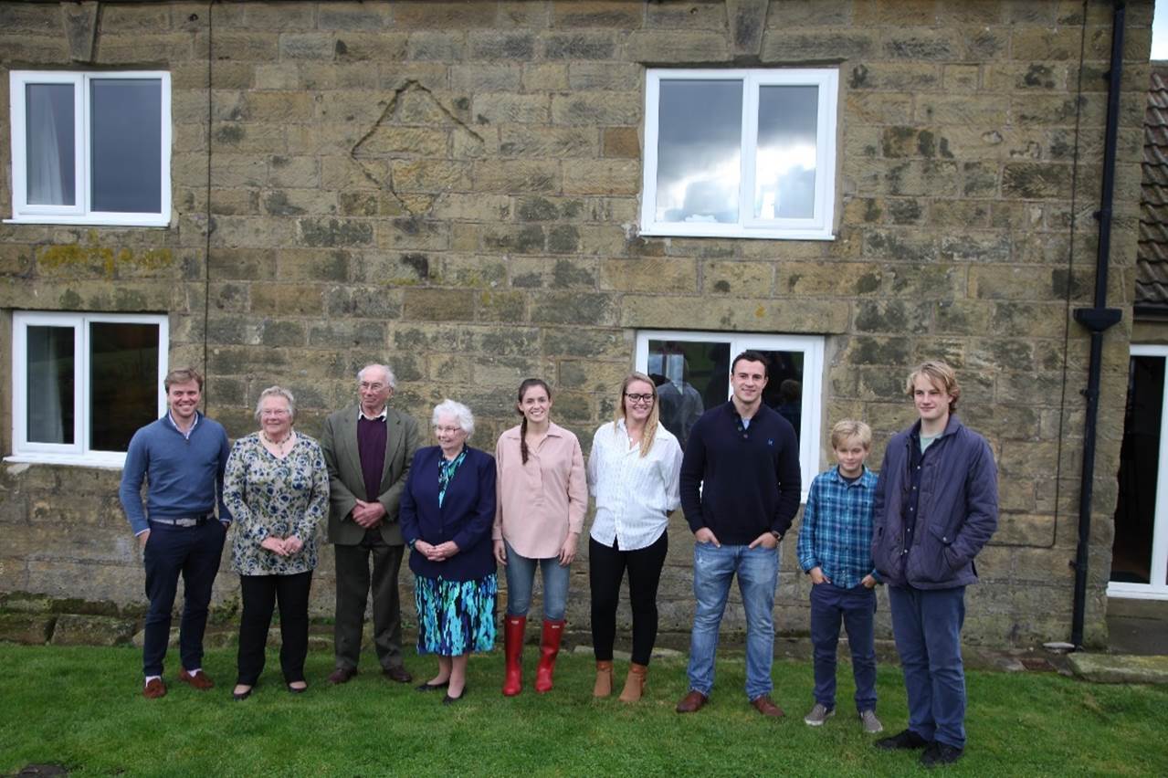 A group of people standing in front of a stone building

Description automatically generated